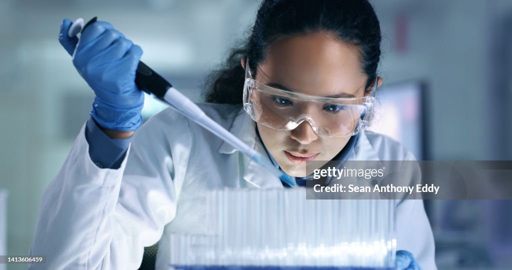 Scientist wearing safety glasses using a pipette in a laboratory
