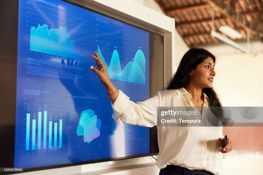 Woman presenting financial charts on a large display